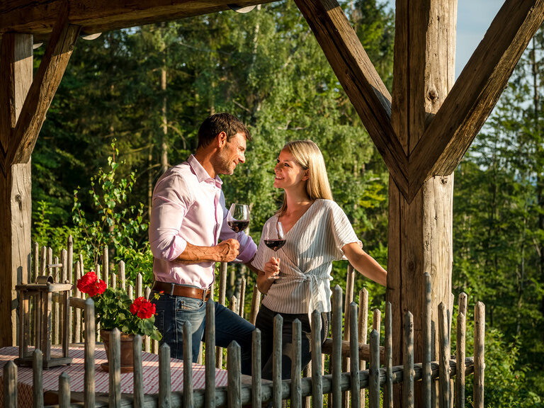 Pärchen auf der Luxus Chalet Bayern Terrasse sieht sich mit Weinglas in der Hand in die Augen