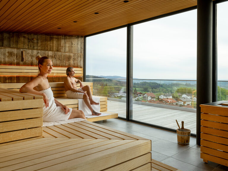 Pool auf sonniger Dachterrasse mit Sonnenschirmen und Waldpanorama vom Hotel Hüttenhof