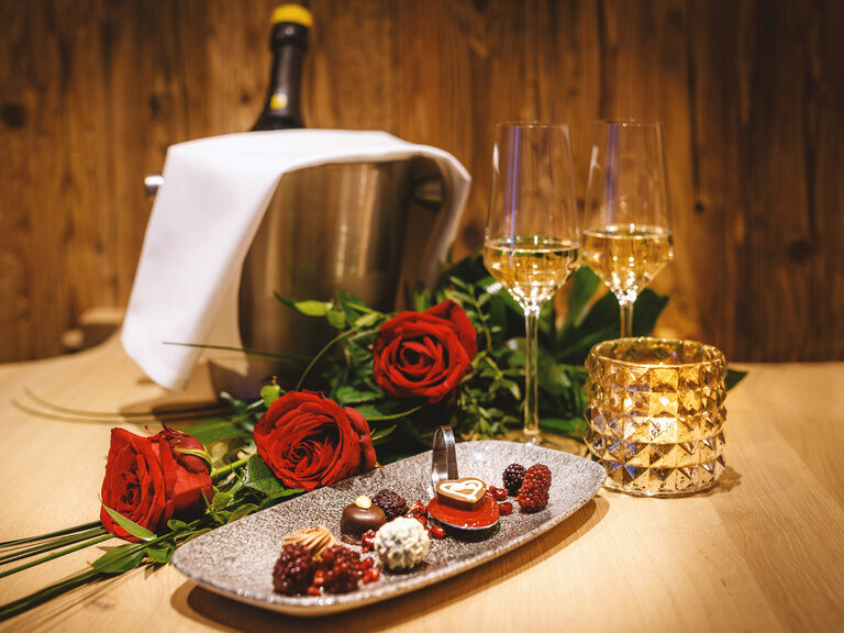 Herrlich angerichteter Pralinenteller mit zwei Gläser Sekt und roten Rosen des 4 Sterne Wellnesshotel Hüttenhof im Bayerischen Wald