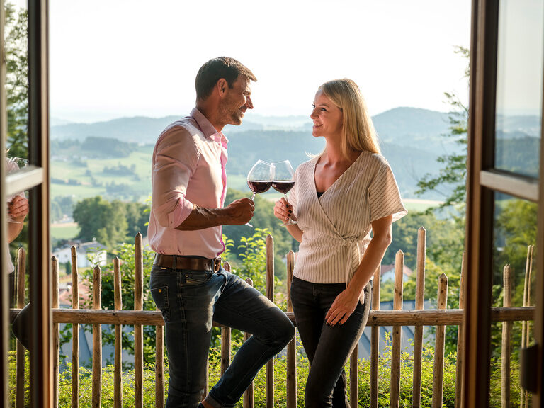 Besondere Momente auf dem Balkon des Chalets genießen Pärchen auf Balkon mit Rotweinglas in der Hand, Ausblick über das Tal