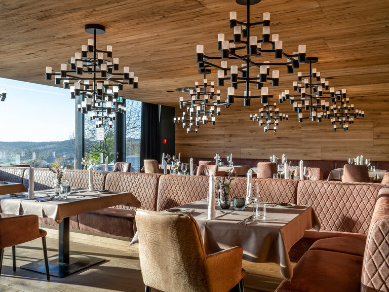 Panorama-Restaurant mit Wildleder-Sitzbank, schwarzen Kronleuchtern und Holzwand- und decke