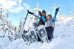Schneeschuhwanderer im Bayerischen Wald im Winter Zwei Schneeschuhwanderer lachen und sitzen im Schnee im Bayerischen Wald