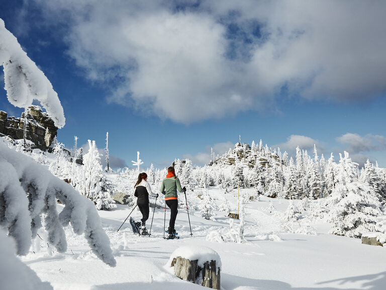Schneeschuhwanderer im Bayerischen Wald im Winter Zwei Schneeschuhwanderer lachen und sitzen im Schnee im Bayerischen Wald