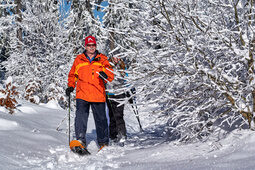 Zwei Personen wandern mit Schneeschuhen durch einen verschneiten Winterwald im Bayerischen Wald.