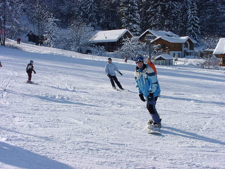 Snowboarderin fährt auf winterlichen Piste im Bayerischen Wald nahe dem Hotel Hüttenhof Snowboarderin fährt auf schneebedeckter Piste im Bayerischen Wald