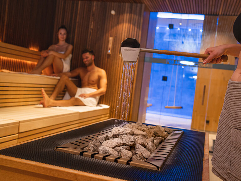 teelicht-in-holzbox-mit-herzfoermigen-loechern-im-4-sterne-wellnesshotel-huettenhof Teelicht in Herz-Holzbox, Rosenblätter und 'Ich liebe dich'-Lichtschrift an der Wand