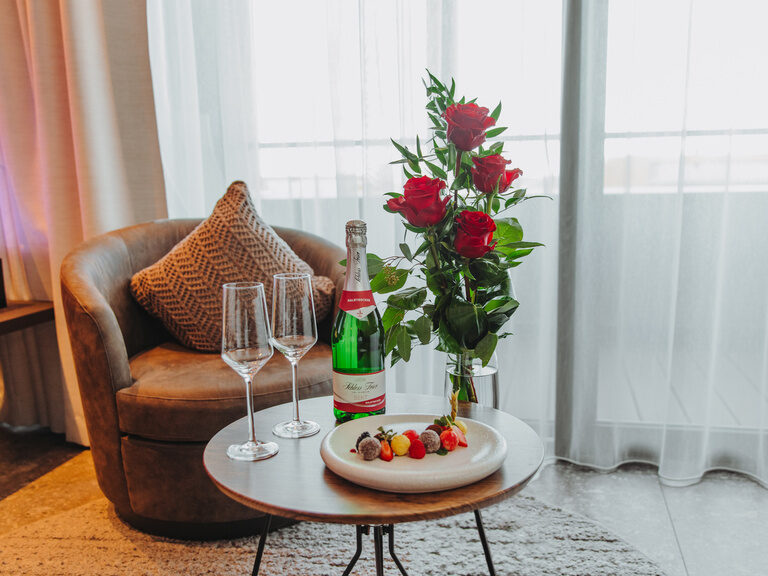 Dessert mit feinen Pralinen und Früchten, auf einem rechteckigem Teller, daneben ein Rosenstrauß