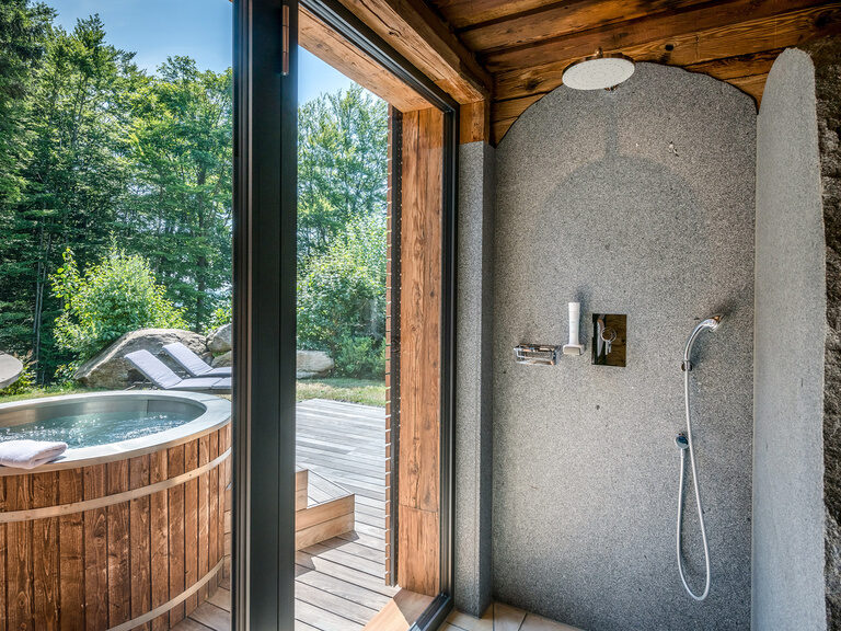 Dusche mit Blick auf die Terrasse mit Whirlpool des Luxus Chalets Bayern