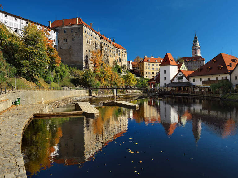 Tschechische Burg neben Altstadt und See, umgeben von Bäumen.