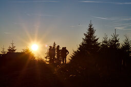 Wandergruppe bei Sonnenuntergang im Bayerischen Wald nahe dem 4-Sterne-Hotel Hüttenhof Wandergruppe bewundert Sonnenuntergang umgeben von Bäumen im Bayerischen Wald