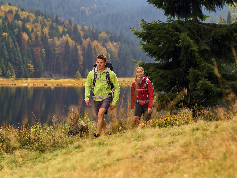 Paar wandert am See im Bayerischen Wald entlang