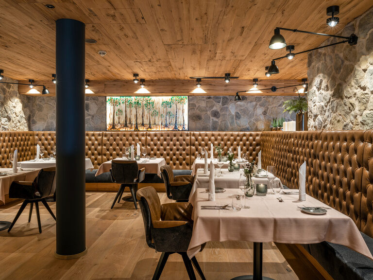 Elegantes Restaurant mit brauner Sitzbank im 4-Sterne-Hotel Hüttenhof Elegantes Restaurant mit brauner Leder-Sitzbank und Steinwand