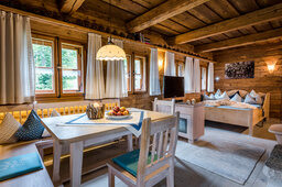 Wohnbereich mit Esstisch und Bett im Luxus Chalet Bayern im Bergdorf Hüttenhof Wohnbereich mit Esstisch und Bett im Luxus Chalet Bayern im Bergdorf Hüttenhof