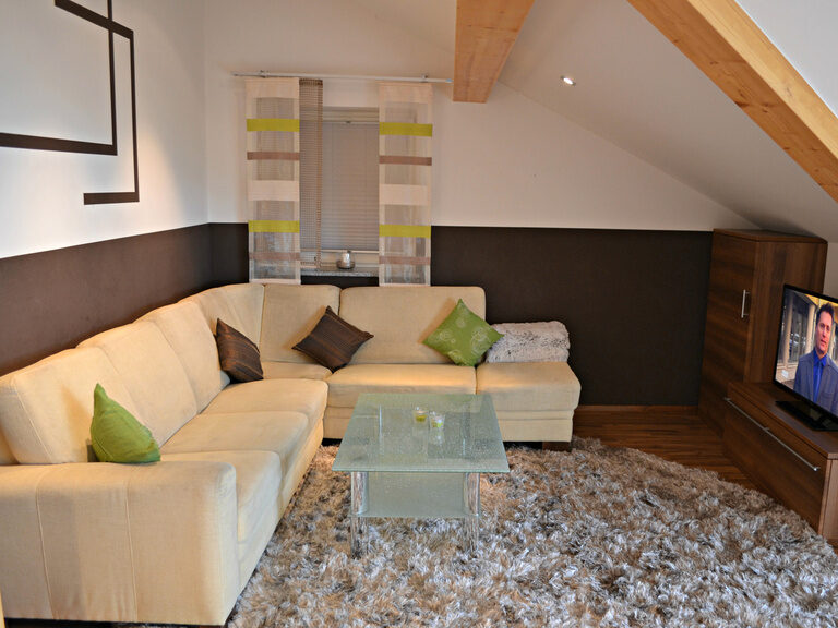 Wohnzimmer mit gemütlichem Sofa, Glas-Couchtisch und gestreiften Fenstergardinen