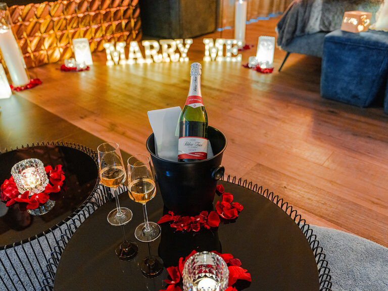 Heiratsantrag-Dekoration mit 'Will you marry me'-Girlande und Kerzen in Zimmer mit Badewanne