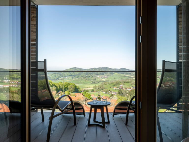 Zwei Liegesessel und runder Beistelltisch auf Balkon mit Blick auf den Bayerischen Wald